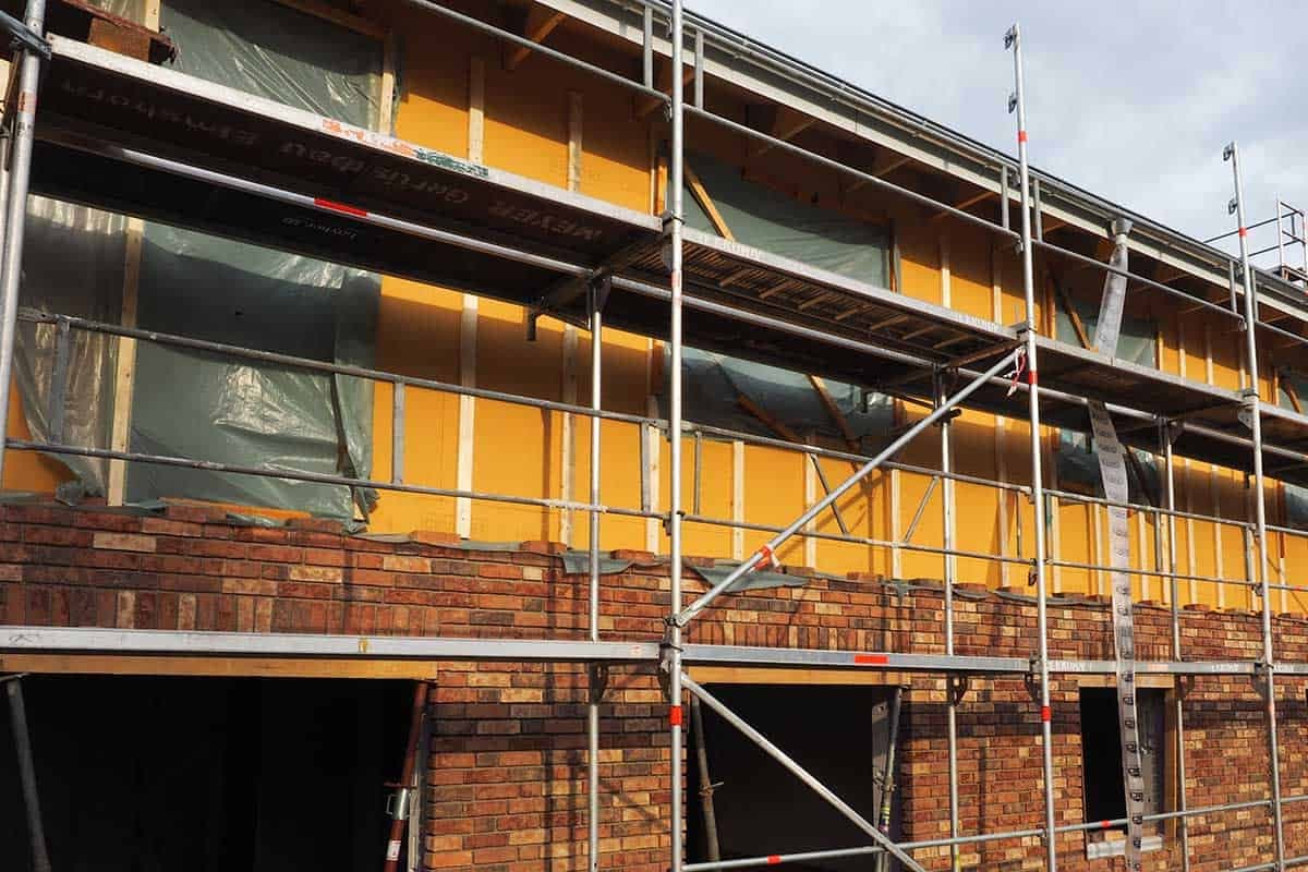 An einer Hauswand wird eine Klinkerfassade mit Kerndämmung hochgezogen