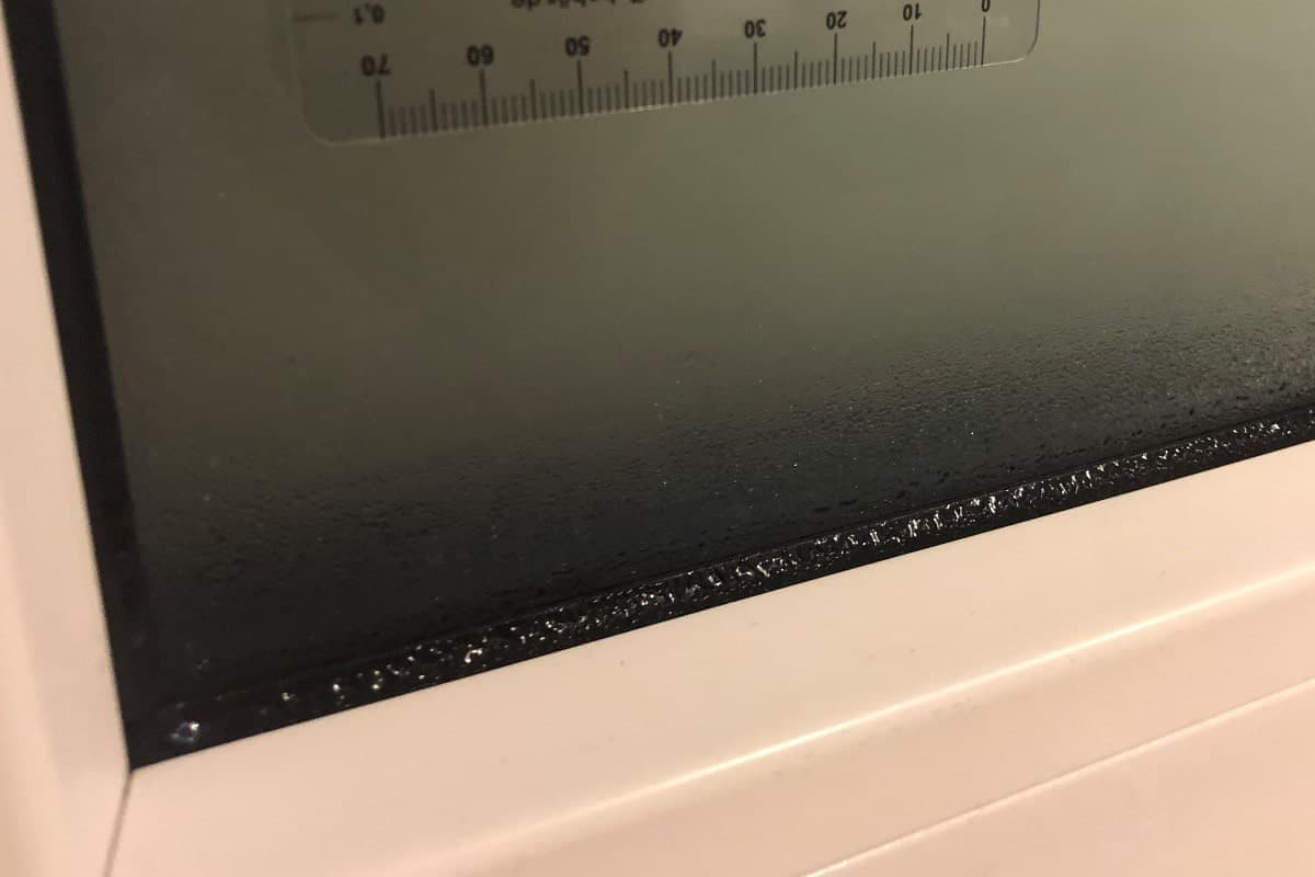 Eine nasse Fensterdichtung mit Scheibe und Fensterrahmen.