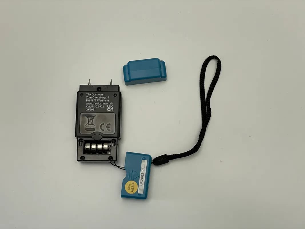 Das TFA Dostmann HumidCheck MINI liegt mit geöffnetem Batteriefach.