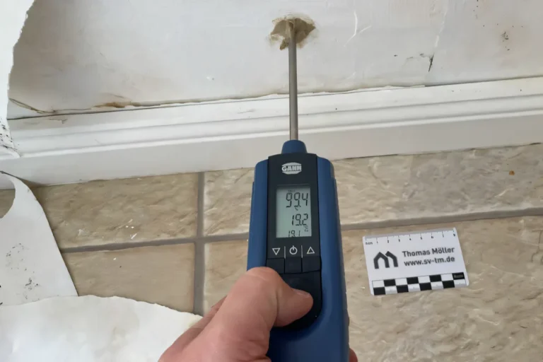 Das Messgerät GANN Hydromette RH-T bei der hygrometrischen Feuchtemessung Messung in einem Bohrloch. Man sieht die Wand die mit Bohrloch, die Sockelleiste und Fliesen.