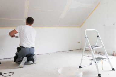 Trockenbauer spachtelt Wand