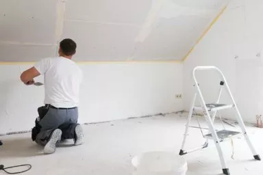 Trockenbauer spachtelt Wand