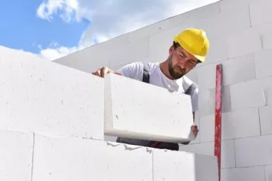 Maurer erstellt Mauerwerk aus Porenbeton mit Dünnbettmörtel