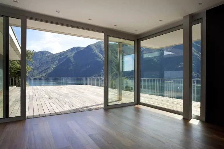 Große Eckfenster mit Schiebeelement vom Wohnzimmer zur Terrasse mit Aussicht auf einen See