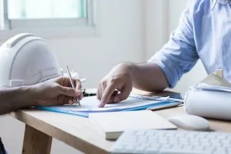 Man zeigt auf die Baubeschreibung.