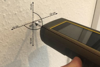 Das Feuchtemessgerät TROTEC T660 wird senkrecht auf die Wand gehalten, um die Wandfeuchte zu messen