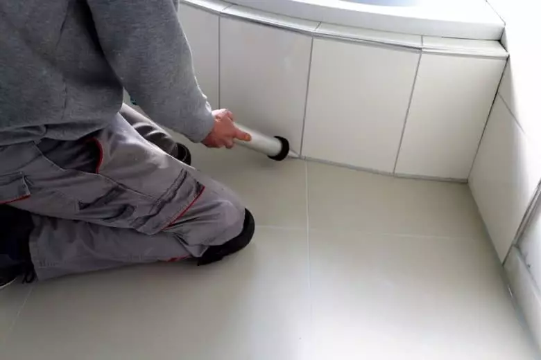 Ein Handwerker verfugt Fliesen im Badezimmer