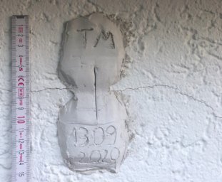 Eine Gipsmarke zur Rissüberwachung in Form einer 8 mit Datum, Kürzel und Kellenschnitt
