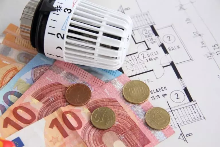 Heizungsthermostat mit Geldscheinen auf einem Bauplan