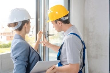 Eine Architektin und ein Handwerker überprüfen Fenster auf der Baustelle