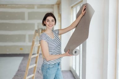 Ein Frau auf der Baustelle wählt eine Tapete aus