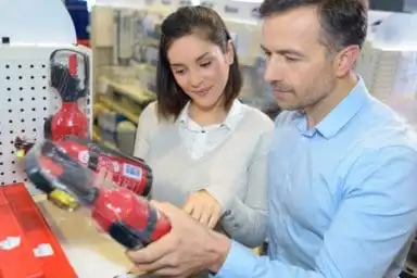 Paar, das Feuerlöscher im Baumarkt vergleicht