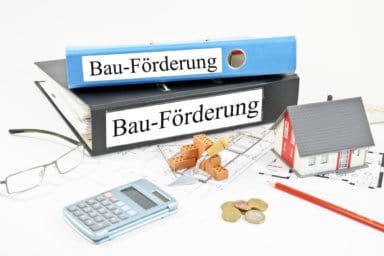 Pläne, Taschenrechner, Hausmodell und Ordner mit Aufschrift Bauförderung